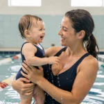 Mère et bébé nageur souriants dans une piscine municipale lors d'un cours de bébés nageurs à Poitiers